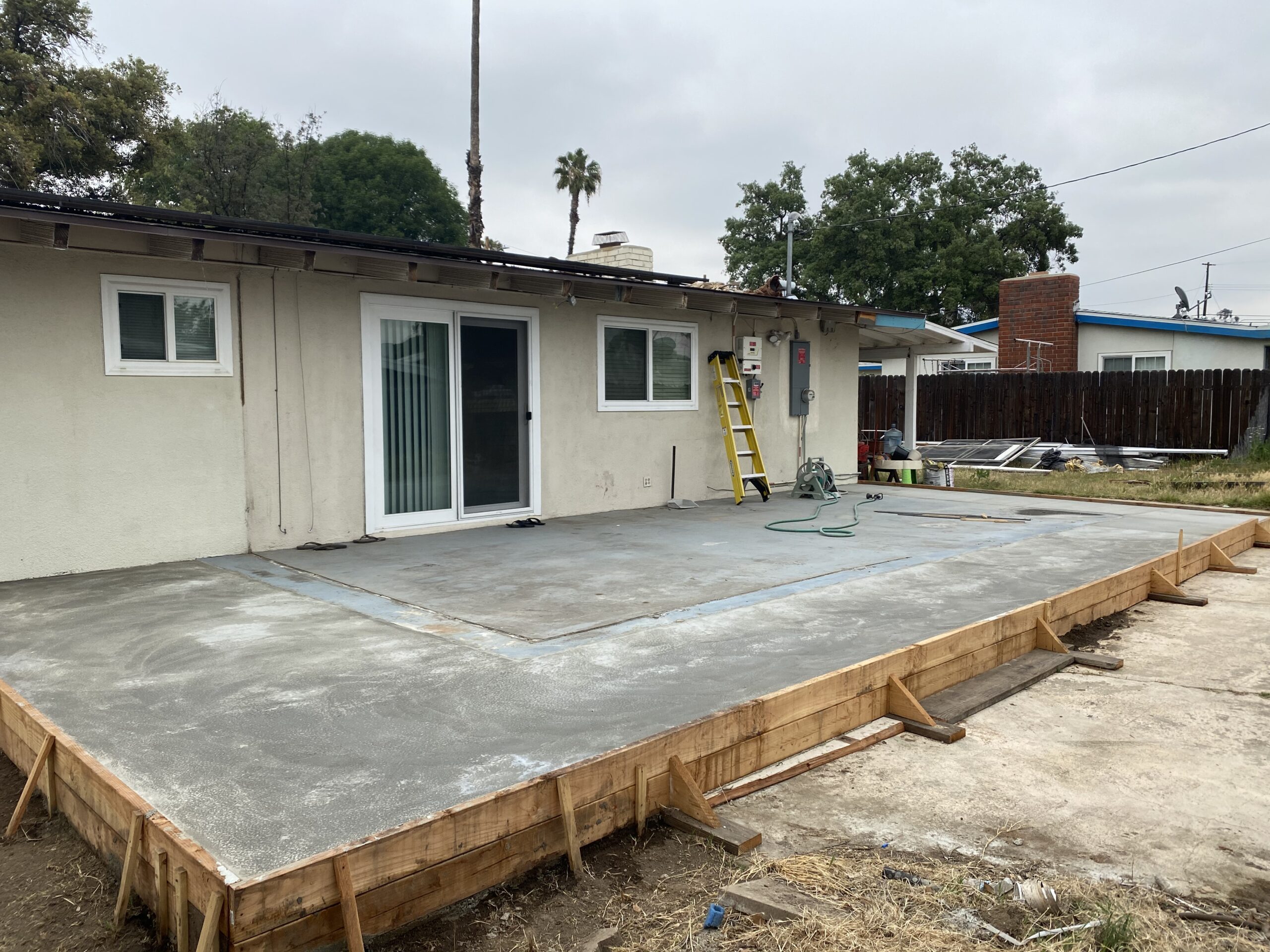 A concrete slab being installed on the side of a house.