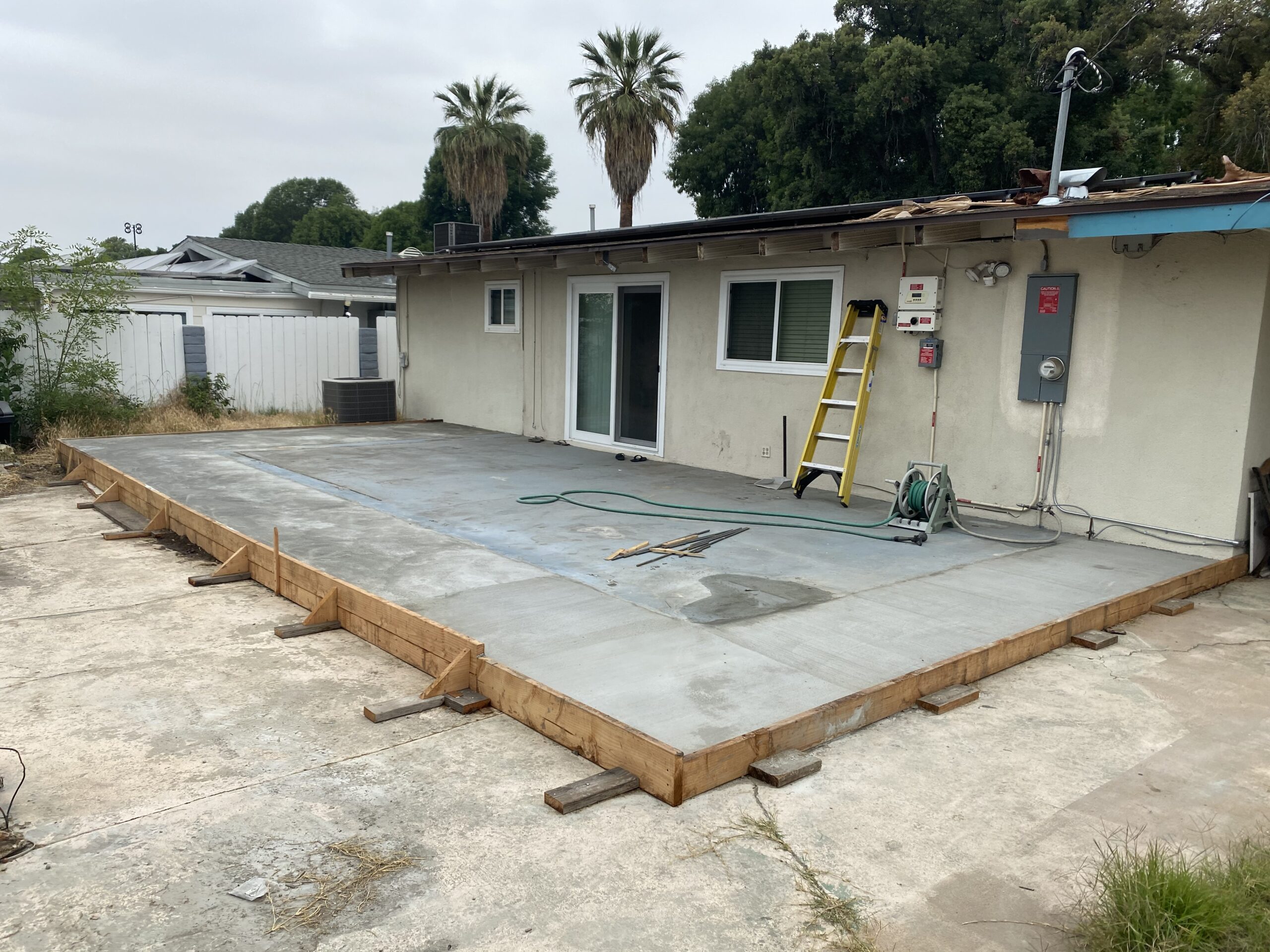 A concrete slab being installed on the side of a house.