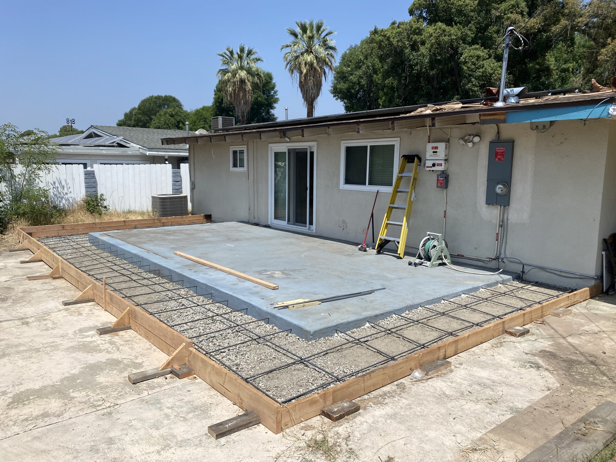 A concrete slab being installed on the side of a house.